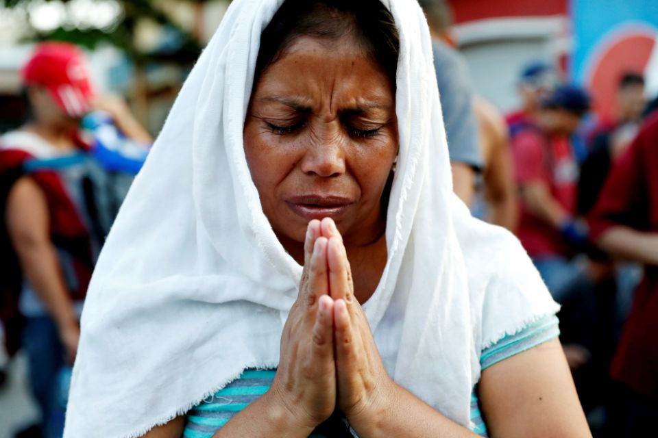 A migrant woman from El Salvador, part of a caravan traveling to the United States, prays during a stop Nov. 2, 2018, in Tecún Umán, Guatemala. (CNS/Reuters/Ueslei Marcelino)