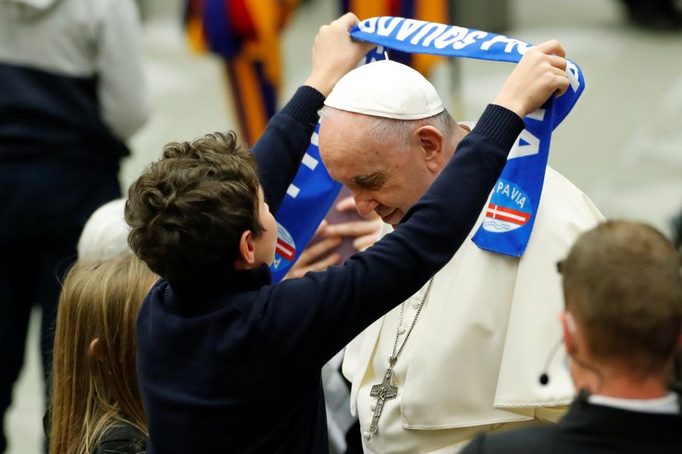 A boy gives Pope Francis a scarf of the Pavia soccer club during the weekly general audience in the Paul VI hall at the Vatican Nov. 17, 2021. (CNS photo/Remo Casilli, Reuters)