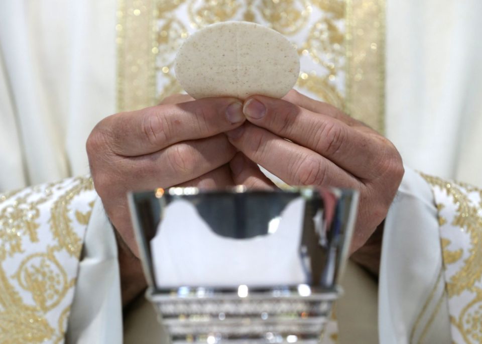 A priest holds the Eucharist in this illustration taken May 27, 2021. (CNS/Bob Roller)