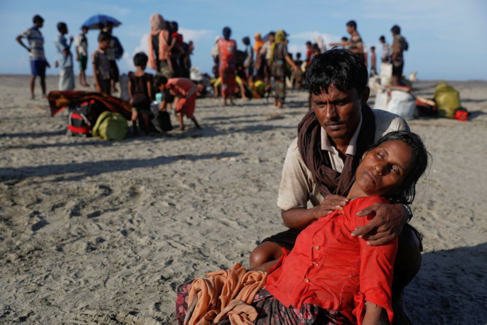 A man who said his village was burned and relatives killed by Myanmar soldiers comforts his wife as Rohingya refugees arrive by a wooden boat from Myanmar in Shah Porir Dwip, Bangladesh, Oct. 1, 2017. 