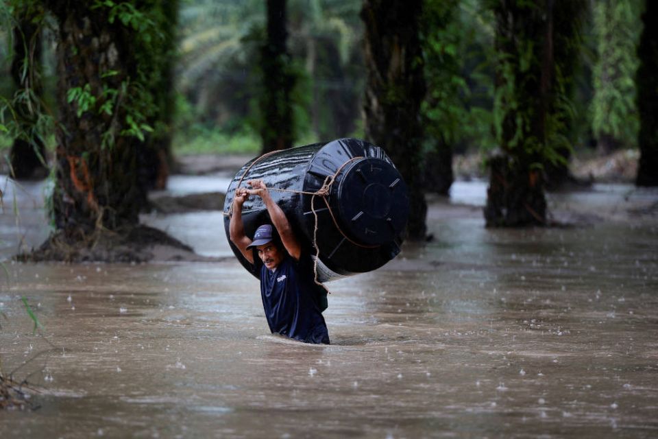 A man carries an empty water tank through a flooded area after the impact of tropical storm Julia in Progreso, Honduras, Oct. 9, 2022. (CNS photo/Yoseph Amaya, Reuters)