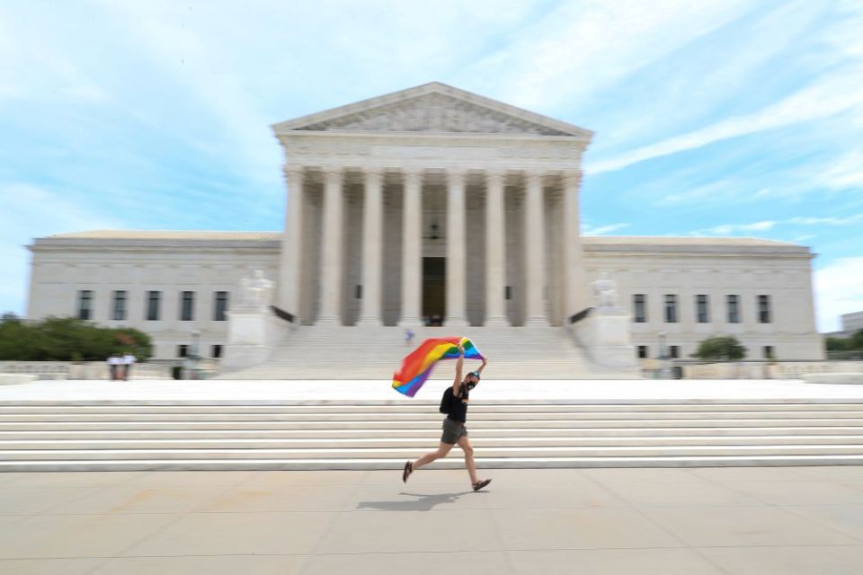 A person runs with a gay pride flag in front of the U.S. Supreme Court building in Washington June 15, 2020. In a 6-3 vote that day, the Supreme Court said LGBTQ people are protected from job discrimination by Title VII of the Civil Rights Act of 1964. 