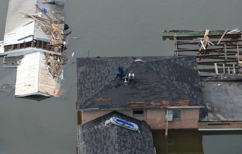 People sit on a roof waiting to be rescued after Hurricane Katrina struk New Orleans in August 2005. (Wikimedia Commons/Jocelyn Augustino/FEMA)