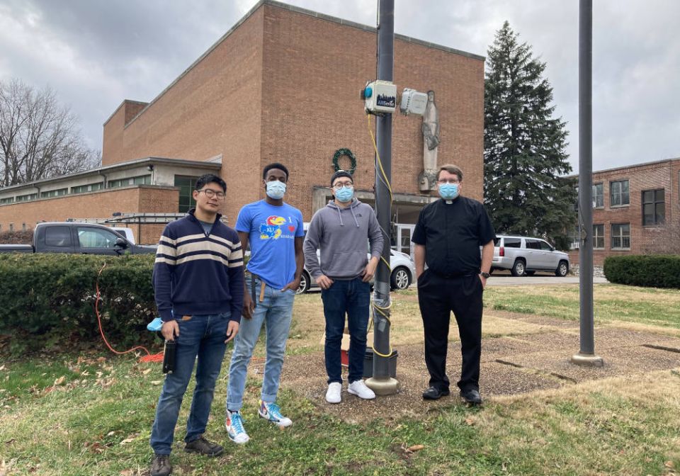 Students from Washington University in St. Louis work with the Rev. Nick Winker to set up an air pollution monitor at St. Ann Catholic Church in St. Louis. (RNS Photo/Beth Gutzler)