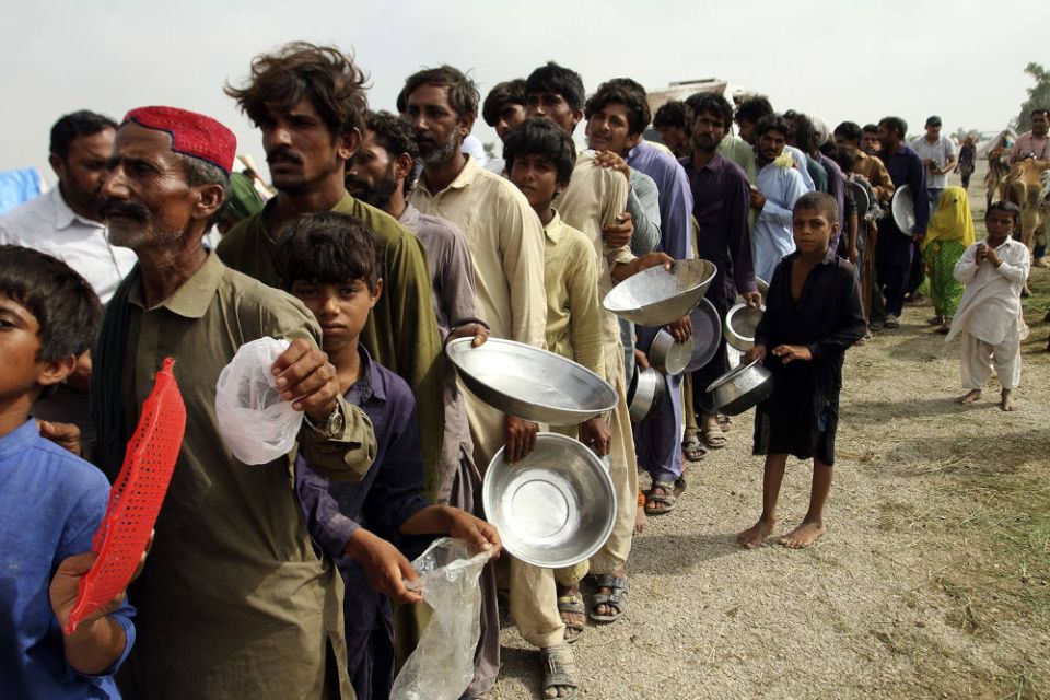 People displaced by flooding wait in a long line to receive food distributed by Pakistani army troops in a flood-hit area in the Rajanpur district of Punjab, Pakistan, Aug. 27, 2022. (AP Photo/Asim Tanveer)