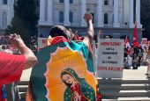 A marcher wearing an Our Lady of Guadelupe flag in Sacramento, Calif., stands in front of the state capitol building Aug. 26, 2022