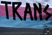 A person holds a "Trans" banner in this illustration photo.