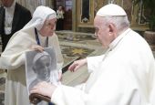 Pope Francis looks at artwork of himself presented by a nun during an audience with the participants of a symposium on "Holiness Today," sponsored by the Dicastery for the Causes of Saints, at the Vatican Oct. 6, 2022