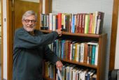 Richard Sipe, in the offices of BishopAccountability.org, points to a collection of his books that he gave to the church watchdog organization. (Courtesy of Fr. Tom Doyle)
