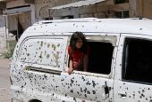 A girl in Daraa, Syria, looks out from a bullet-riddled bus July 9, 2017. Syria's civil war has now entered its 10th year. (CNS/Reuters/Alaa Al-Faqir)