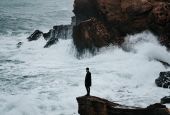 Man standing on rocky shore of Algeria (Unsplash/Benoumechiara)