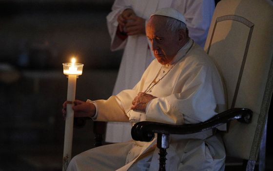 Pope Francis holds a candle as he attends the Easter Vigil celebrated by Cardinal Giovanni Battista Re in St. Peter's Basilica at the Vatican April 16. (CNS/Paul Haring)
